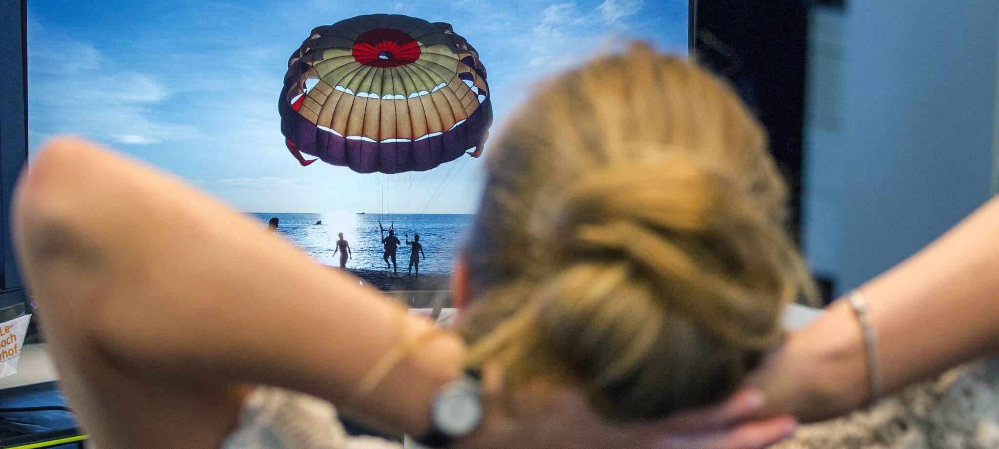 Frau auf einem Bürostuhl schaut auf ein Reisefoto
