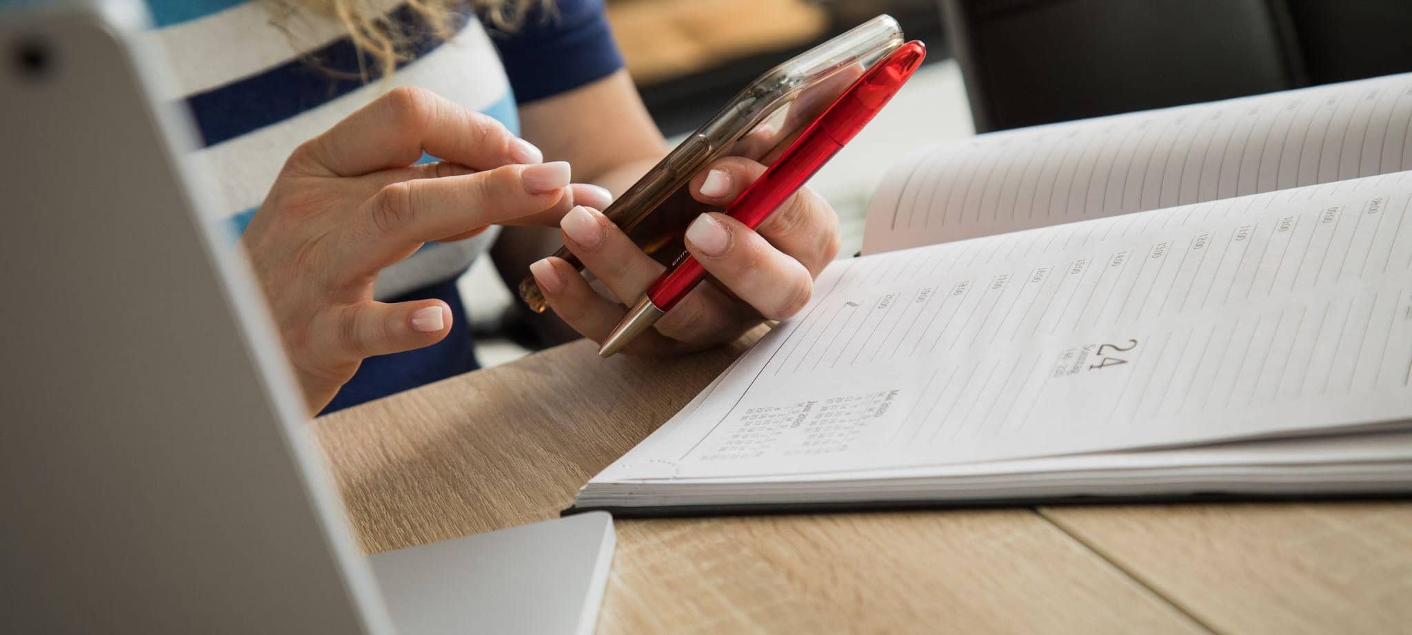 Eine Frau mit Handy, Laptop und Kalender